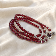 Garnet lotus heart wrap bracelet on warm ivory linen