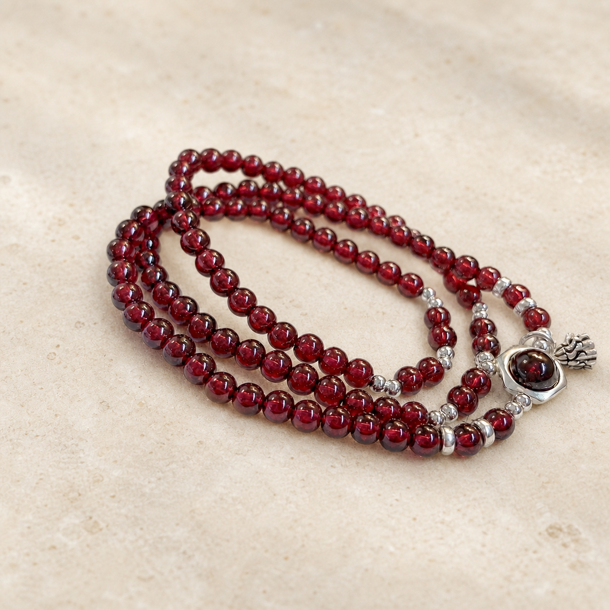 Garnet lotus heart bracelet on warm ivory stone