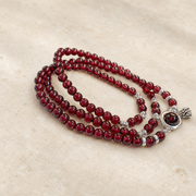 Garnet lotus heart bracelet on warm ivory stone