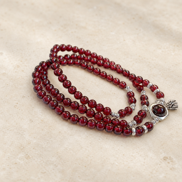 Garnet lotus heart bracelet on warm ivory stone