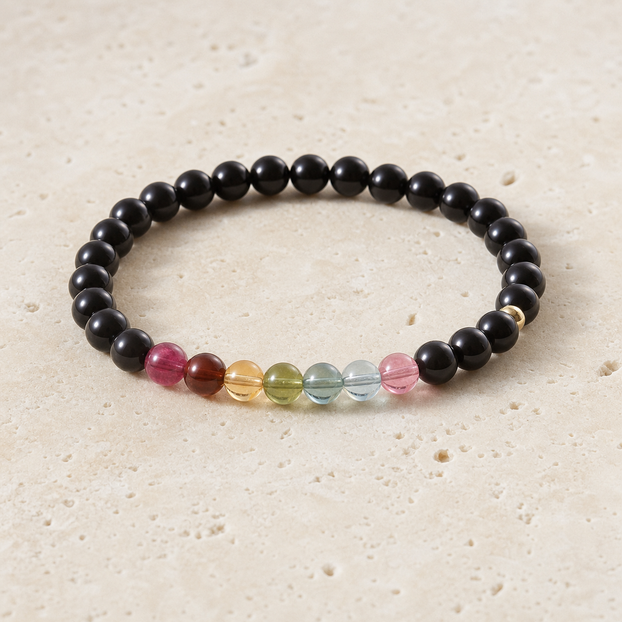 Obsidian and tourmaline bracelet on warm ivory stone